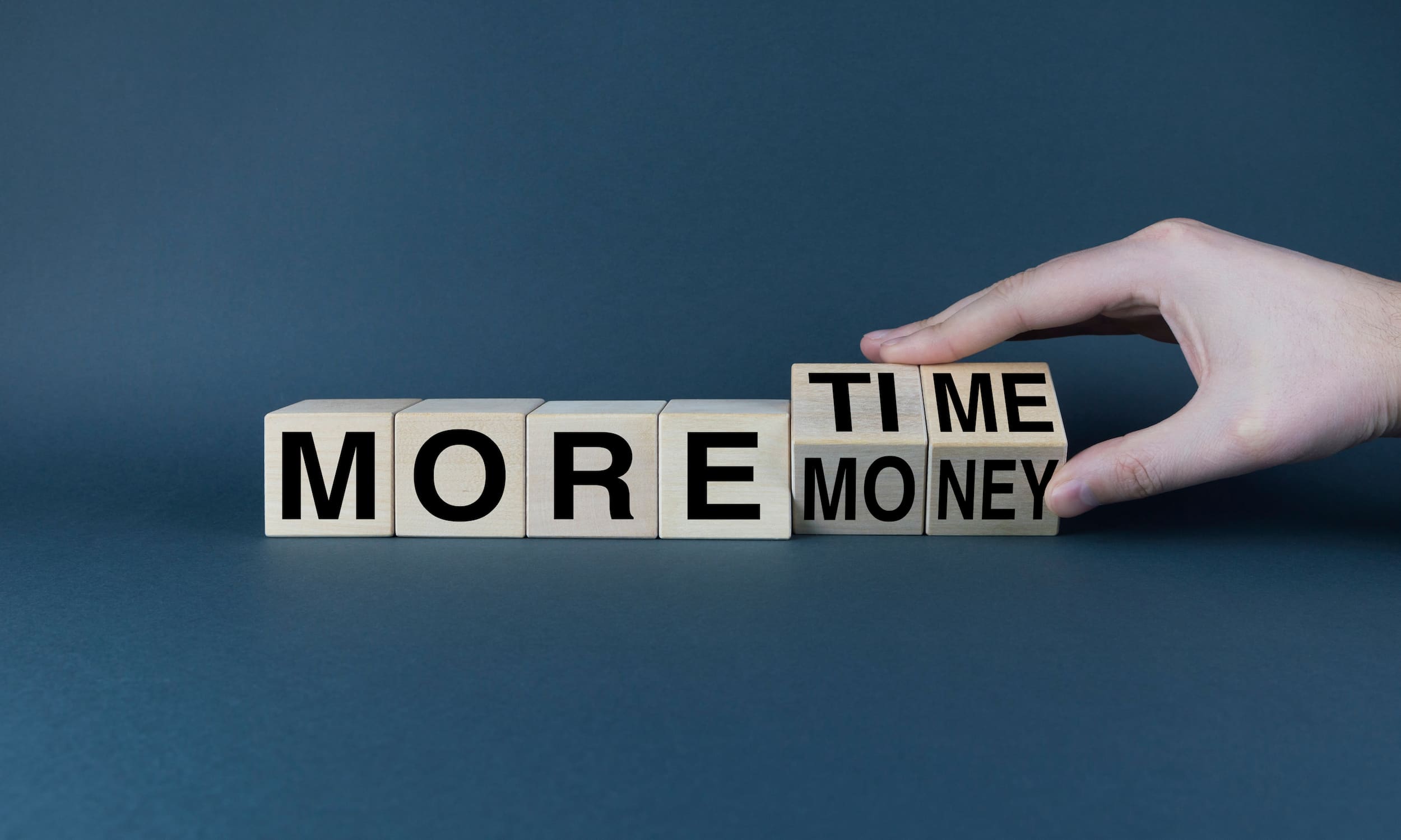 jeu-mot-bois-temps-argent-plus-message Cubes en bois formant le mot « money » à côté d'une horloge